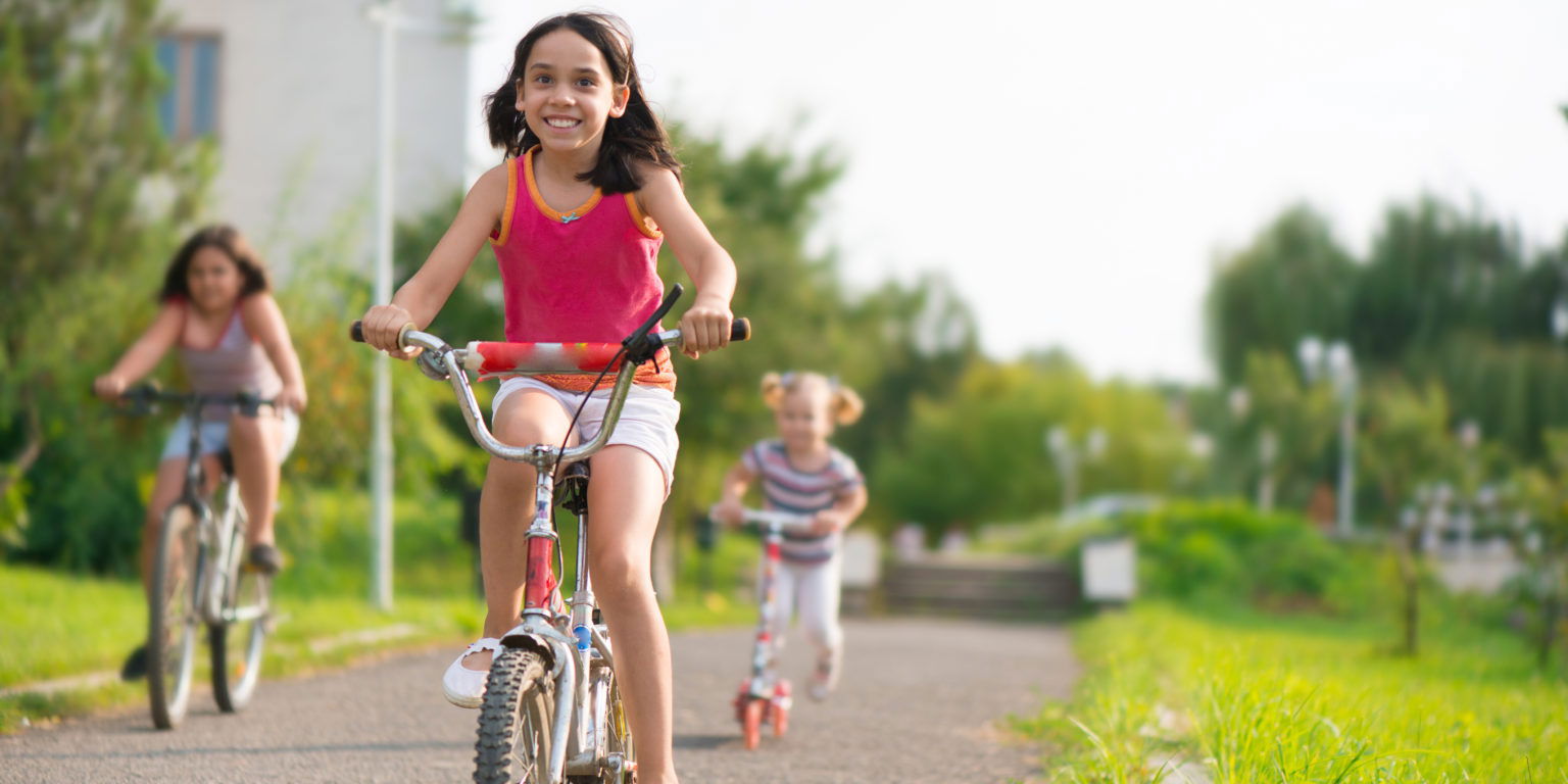 Three happy children riding on bicycle